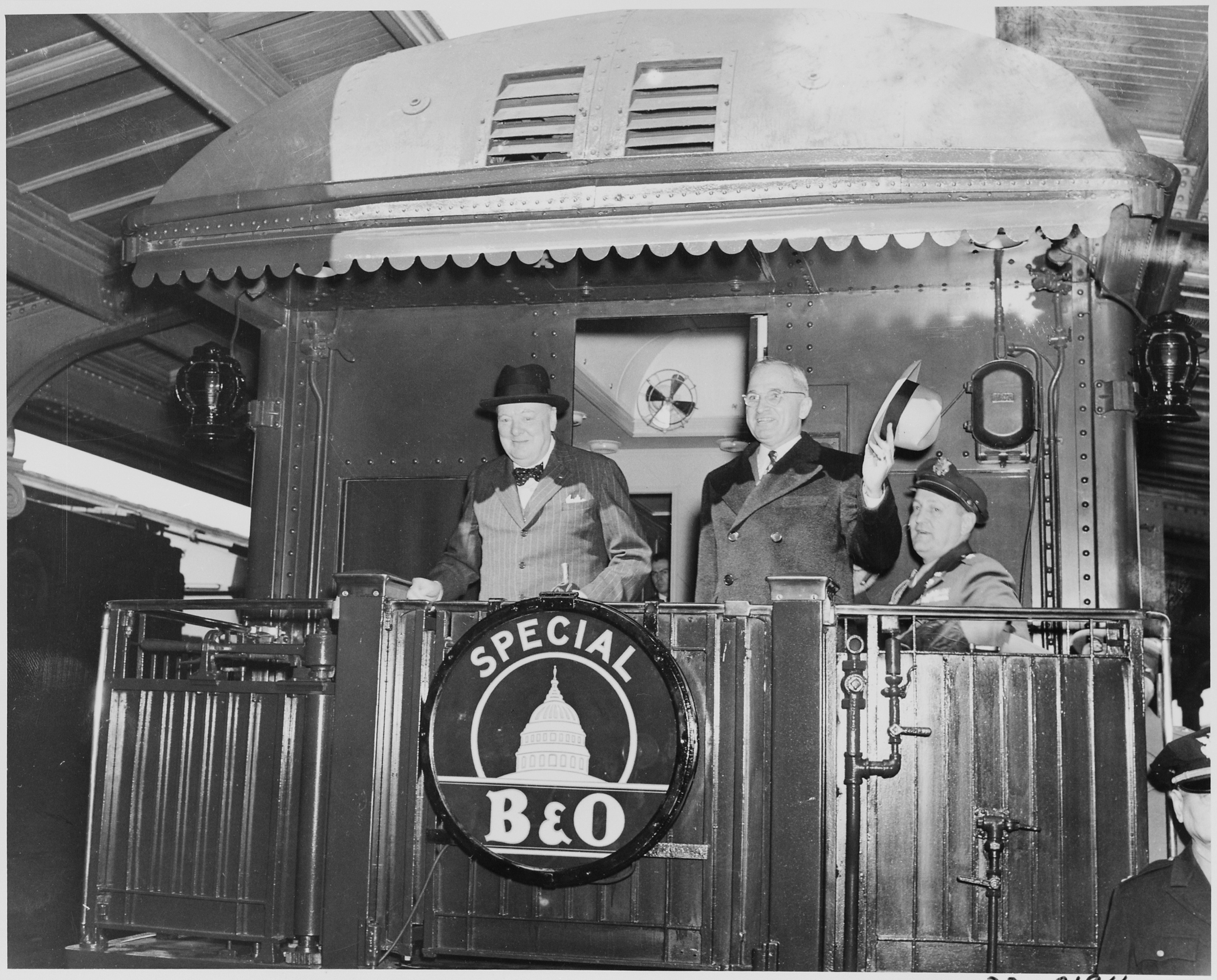 Harry S. Truman y Winston Churchill saludan desde la trasera de un tren especial Baltimore & Ohio camino de Fulton (Misuri), 5 de marzo de 1946.